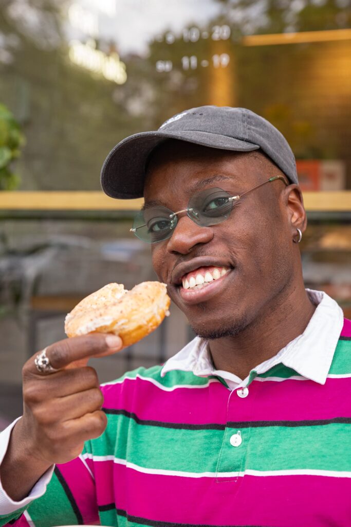 Justice holding a poppy seed lemon donut and smiling into the camera.